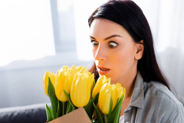 shocked woman with pollen allergy looking at tulips  - Photo, Image