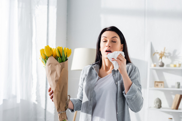 attractive woman with pollen allergy sneezing while holding tulips  - Photo, Image