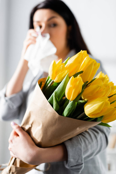 selective focus of tulips in hand of woman with pollen allergy and running nose - Foto, Imagen