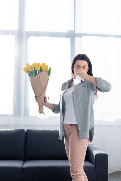 kichająca kobieta z alergią na pyłki i zamkniętymi oczami trzymająca tulipany  - Zdjęcie, obraz