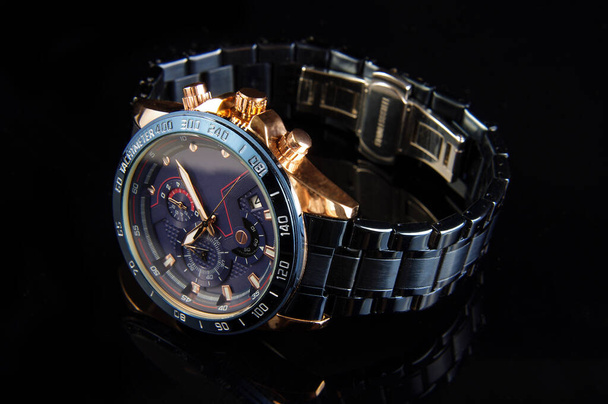 Professionelle Luxus goldblaue männliche Uhr auf der schwarzen reflektierenden Oberfläche - Foto, Bild