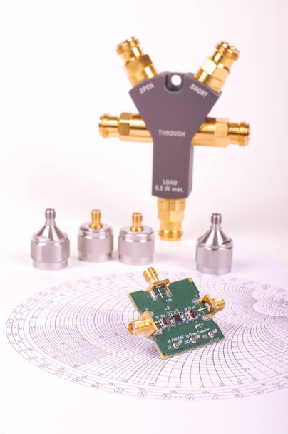 Placa de circuito impreso mezclador de radiofrecuencia delante del gráfico Smith y otras herramientas de medición de microondas
 - Foto, Imagen