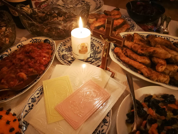 Litewski stół wigilijny z opłatkami świątecznymi, świecami i różnymi daniami - Zdjęcie, obraz