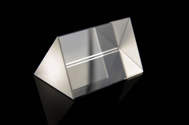 Triangular optical prism for scientific experiments isolated on the black reflective background - Photo, Image