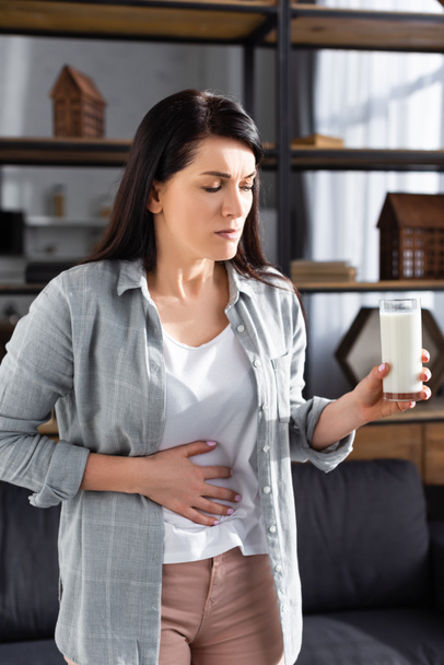 traurige Frau mit Laktoseintoleranz hält Glas Milch in der Hand  - Foto, Bild