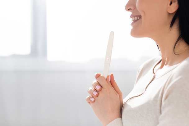 cropped view of cheerful woman holding pregnancy test  - 写真・画像