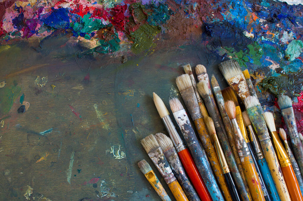 Munkahelyi festő paletta színekkel és ecsetekkel. Színezékek palettája, kreatív zavar, művészet. - Fotó, kép