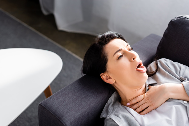 sick woman coughing while lying on sofa  - Фото, зображення