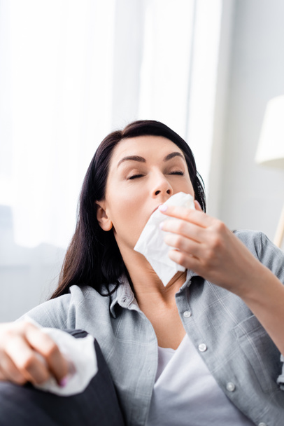 selective focus of allergic woman sneezing and holding napkins  - Photo, Image