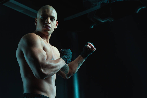 Handsome muscular man standing shirtless in a boxing stance and looking into the distance - Фото, зображення