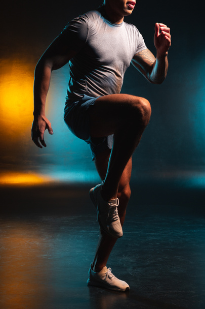 Foto recortada de un deportista calentando sus músculos y poniendo una rodilla
 - Foto, imagen