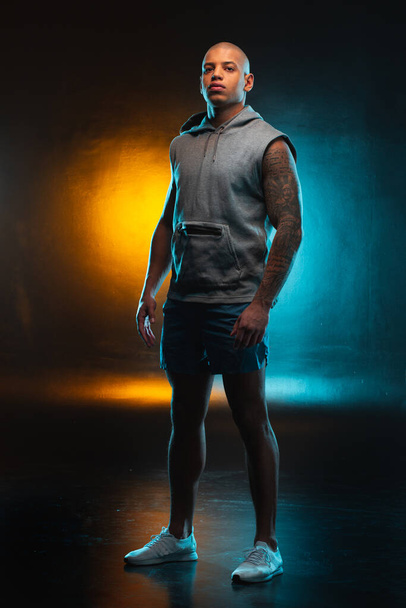 Calm young man in casual clothes looking confident. Orange and teal light on the background - Photo, Image