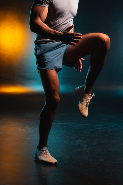 Ritagliato foto di uomo in scarpe sportive mettendo su un ginocchio
 - Foto, immagini