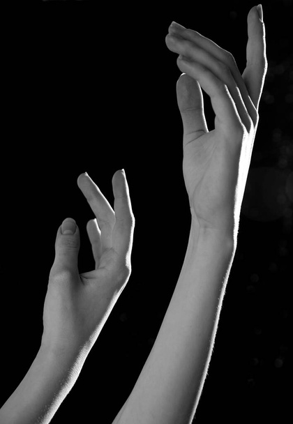 De sierlijke bocht van de armen van de ballerina, op een zwarte achtergrond - Foto, afbeelding