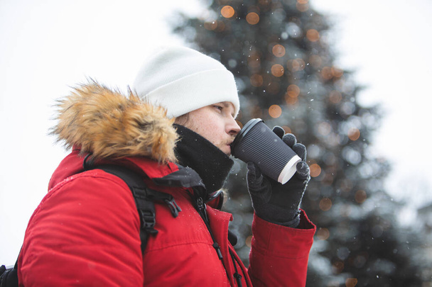 чоловік на відкритому повітрі п'є каву з паперової чашки зимовий час розігрівати червоне пальто
 - Фото, зображення