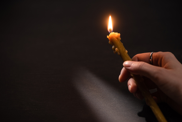 vista recortada de la mujer sosteniendo vela de iglesia en llamas en la oscuridad
 - Foto, Imagen