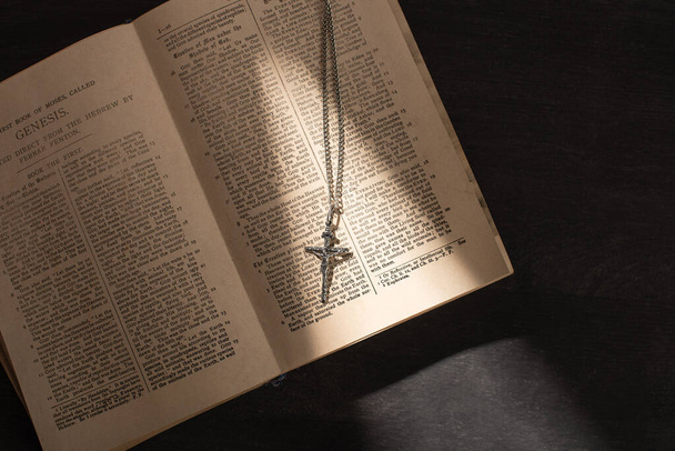 KYIV, UKRAINE - JANUARY 17, 2020: top view of open holy bible with cross on dark background with sunlight - 写真・画像