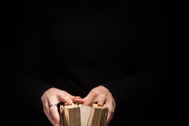 oříznutý pohled na ženu držící svatou bibli izolovanou na černém - Fotografie, Obrázek