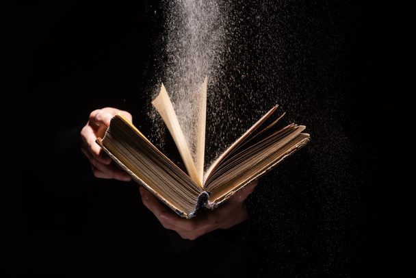 cropped view of woman holding holy bible with dust on black background - Photo, Image