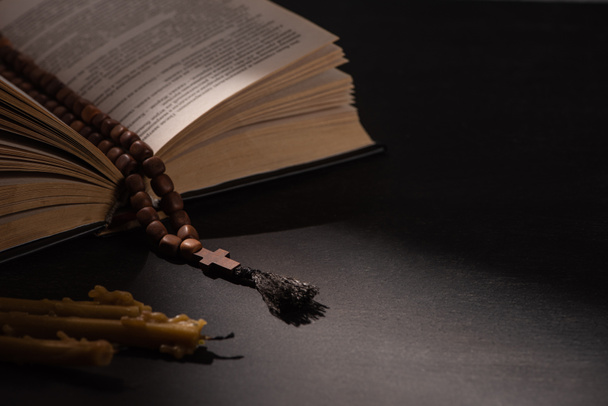 holy bible with rosary on black dark background with candles - Photo, Image