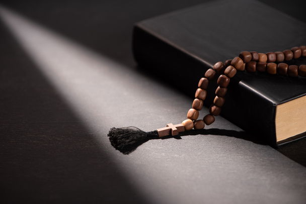 holy bible with rosary on black dark background with sunlight  - 写真・画像