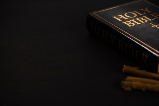 messa a fuoco selettiva della Sacra Bibbia e candele su sfondo nero scuro
 - Foto, immagini
