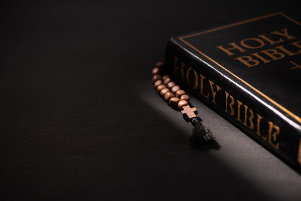 szent biblia rózsafüzérrel fekete sötét háttér - Fotó, kép