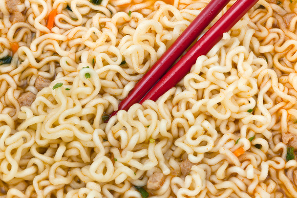 τρώει στιγμιαία noodles από κόκκινο τσοπ στικς - Φωτογραφία, εικόνα