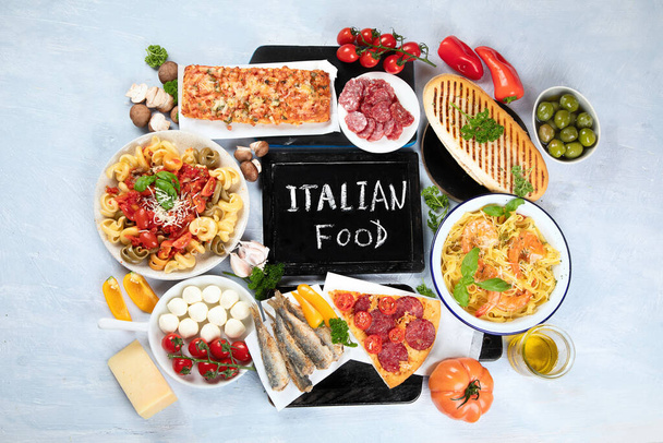 Traditionelle italienische Küche mit Pizza, Pasta, Oliven, Gemüse. Gesunde mediterrane Ernährung. Draufsicht mit Kopierraum - Foto, Bild