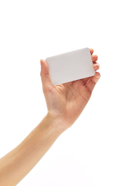 asiático hembra mano sostiene blanco vacío papel tarjeta en un blanco fondo
. - Foto, Imagen
