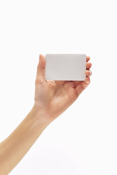 asian female hand holds white empty paper card on a white background. - Fotó, kép