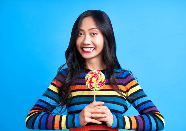 Happy beautiful woman with colorful lollipop isolated on blue background. Sweet food, enjoying concept                             - Foto, immagini