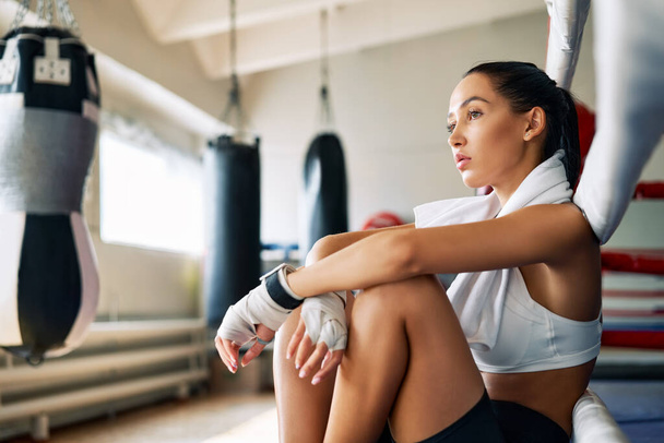 Young beautiful woman relax after fight or workout exercising in boxing ring. Sport concept - 写真・画像