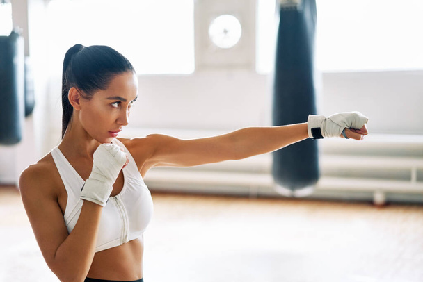Female boxer practicing her punches at a boxing studio.  Athletic woman making direct hit. Sport concept                           - Foto, afbeelding