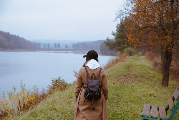 秋の服装で湖畔を歩く女は - 写真・画像