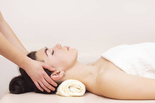 head and temporal massage in a spa salon for a girl. concept of health massage. light background. - Foto, Bild