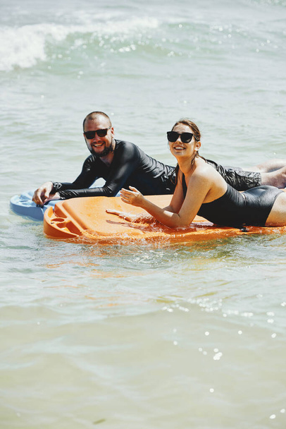 Χαρούμενος νεαρός άνδρας και γυναίκα απολαμβάνοντας το κολύμπι με πλαστικά στρώματα μαζί στη θάλασσα - Φωτογραφία, εικόνα