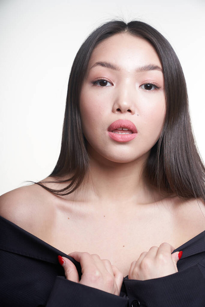  Portrait of a young beautiful Asian girl looking directly at the camera, shoulders open, hands pressed to her chest. The concept of skin care facial, makeup                                                     - Fotografie, Obrázek