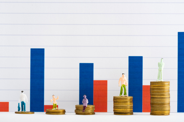 Persone figure sulle monete su superficie bianca con grafici sullo sfondo, concetto di uguaglianza finanziaria
 - Foto, immagini