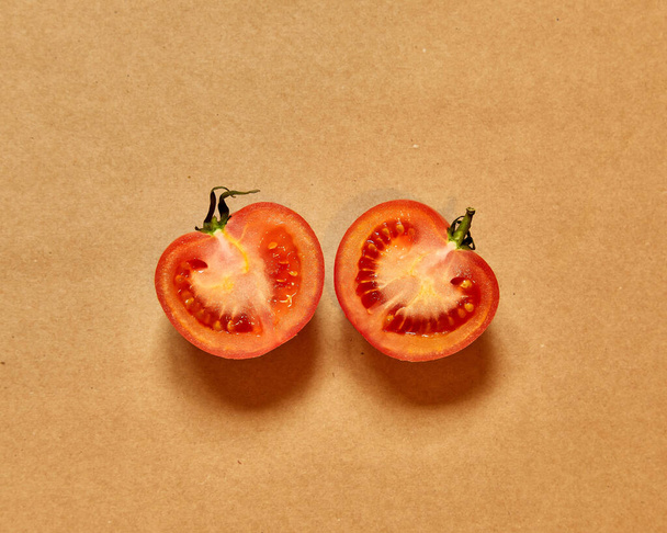 Red tomato cut in half isolated in a brown background viewed from above - flatlay look - Photo, Image