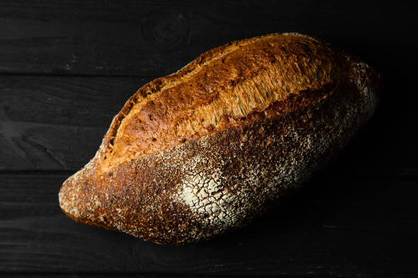 Rye bread ciabatta on a black wooden background - Foto, afbeelding