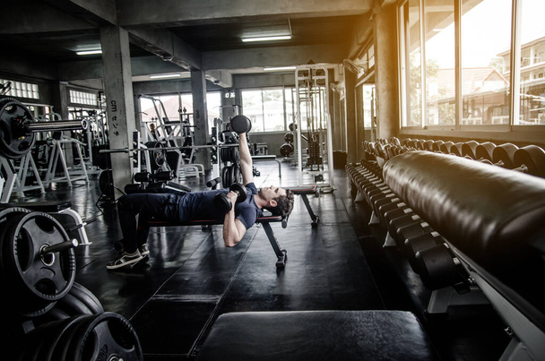 hombre recogida dumbell en el gimnasio. ejercicio con el programa de entrenamiento para la salud
 - Foto, Imagen