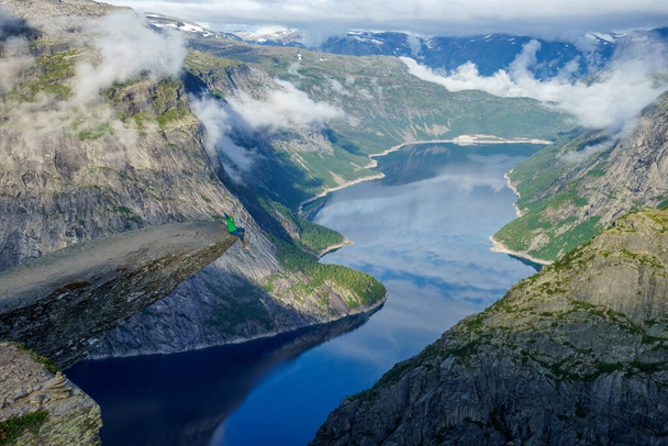 Brave man sitting on the edge Trolltunga. Norway - Zdjęcie, obraz