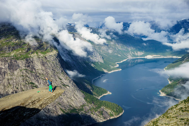 Gymnast standing on his hands on the edge with fjord on background near Trolltunga. Norway - 写真・画像