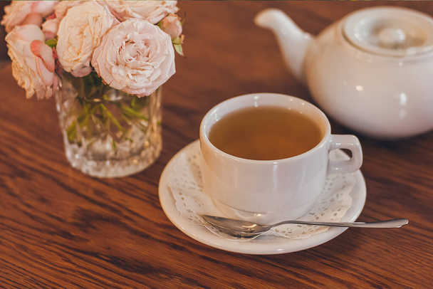 Piękne świeże róże w pobliżu filiżanki herbaty i w pastelowych kolorach romantyczny nastrój. - Zdjęcie, obraz