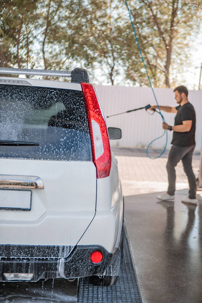 сильний чоловік миє машину в автомийці на відкритому повітрі літній час
 - Фото, зображення