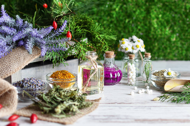 Variety of herbs and herbal mixtures as an alternative medicine concept on wooden table background over green grass. Homeopathy treatment. - Photo, Image