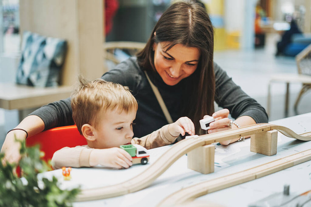 Cute baby boy maluch dziecko z matką grać z zabawek samochodowych w pokoju gier w centrum handlowym - Zdjęcie, obraz