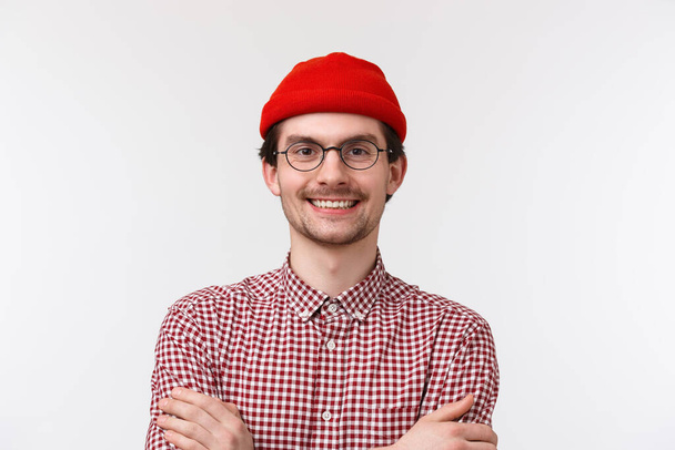 Lähikuva muotokuva luottavainen iloinen nuori mies ilmaisee itseään kirkas asu, käyttää hipster punainen pipo ja tarkistettu paita, rajat kädet rinnassa kuin ammattilainen, hymyillen iloinen, valkoinen tausta
 - Valokuva, kuva