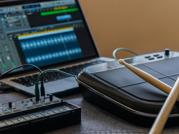 Close up of an electronic battery with drumsticks, an fm synthesizer and a laptop with a music editor. Music concept. - Foto, immagini